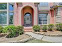 Close-up of the brick archway, front door with a wreath, and stone walkway with landscaped bushes at 5915 Masters Club Dr, Suwanee, GA 30024