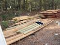 Various lumber and wood planks stacked on the ground outdoors at 1386 Highway 92 S, Fayetteville, GA 30215