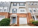 Brick front of a three-story townhouse with a two-car garage and landscaping at 3944 Howell Park Rd, Duluth, GA 30096