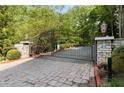 View of the decorative wrought iron gate, brick gate columns, and brick paver driveway leading to the property at 3280 Stillhouse Se Ln # 305, Atlanta, GA 30339