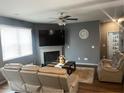 Cozy living room boasts a fireplace, ceiling fan, neutral color palette, and a plush leather sofa set at 11547 Hathaway Dr, Hampton, GA 30228