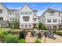 Stunning two-story townhouse featuring a brick patio with an outdoor fire pit and chairs, complemented by landscaped grounds at 396 Silverbell Way, Marietta, GA 30060