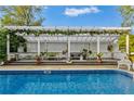 Beautiful outdoor patio with white pergola, greenery, and comfortable seating, ideal for enjoying the serene poolside view at 3532 South Fulton Ave, Hapeville, GA 30354