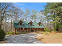 Log cabin home nestled in a wooded area with a gravel driveway at 135 Fiddle Crk, Social Circle, GA 30025