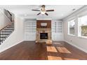 Bright living room with a stone fireplace flanked by built-in shelving, hardwood floors, and large windows for natural light at 333 Gardens Of Harmony Dr, Canton, GA 30115