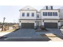 Two story townhome with white brick exterior, two-car garage, and landscaping at 706 Dodd Ln # 157, Buford, GA 30518