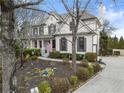 Side view of an elegant two-story home featuring a charming front porch and lush landscaping at 6310 Fox Creek Dr, Cumming, GA 30040