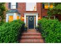 Elegant brick entrance with a black front door, decorative wreath, and lush greenery at 4222 Honey Creek Way, Powder Springs, GA 30127