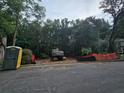 Construction site with heavy equipment and a portable toilet, surrounded by trees and safety barriers at 3910 W Cooper Lake Se Dr, Smyrna, GA 30082
