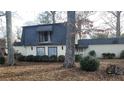 House exterior showcasing a unique roofline, landscaping, and a tree-lined yard at 1221 Kenyon Rd, Lake City, GA 30260