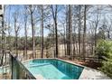 In-ground pool surrounded by mature trees and overlooking a large backyard at 6455 Rutherford Pl, Suwanee, GA 30024