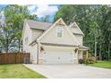 Craftsman style home with light siding, a two car garage, and landscaped front yard on a sunny day at 61 Harmony Woods Ln, Dallas, GA 30157