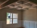 Elegant dining room showcases a coffered ceiling, wainscoting, and a large window overlooking the yard at 8970 Callaway Dr, Winston, GA 30187