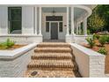 Brick steps leading to a gray front door with a porch at 11577 Serenbe Ln, Chattahoochee Hills, GA 30268