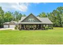 Beautiful home with a spacious front lawn, covered front porch, and a detached three-car garage at 764 Little Vine Church Rd, Villa Rica, GA 30180