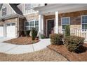 Inviting front porch with stone accents, manicured bushes, and a well maintained lawn at 6170 Pierless Lndg, Sugar Hill, GA 30518