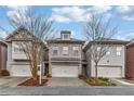 Three townhouses with brick and siding exteriors, two-car garages, and landscaping at 2251 W Village Ln, Smyrna, GA 30080