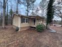 Tan house with black shutters and a tree in front at 6871 Lakeshore Dr, Douglasville, GA 30135