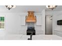 Modern kitchen with white cabinets, marble countertops, and a wooden hood at 153 Palisade Dr, Rydal, GA 30171