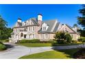 Grand brick home with manicured lawn and circular driveway at 4000 Heatherwood Way, Roswell, GA 30075