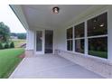 Covered patio featuring brick accents, ample sunlight, and access to the home's interior through glass doors at 5320 Memento Trace, Cumming, GA 30040