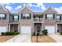 Inviting townhome exteriors featuring brick and siding, individual garages, and covered entrances, set against a bright sky at 7174 Fringe Flower Dr # 21, Austell, GA 30168
