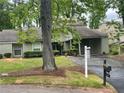 Well-maintained front yard features mature trees, an asphalt driveway, and a home with a covered carport at 104 Woodhaven Way, Alpharetta, GA 30009