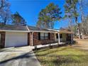 Charming single-story home featuring a brick facade, attached garage, and manicured front yard with mature trees under a blue sky at 432 Independence Dr, Jonesboro, GA 30238