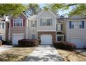 Charming two-story townhome featuring a one car garage, gray shutters, and manicured shrubs at 5665 Terremont Cir, Norcross, GA 30093
