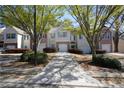 View of townhomes with attached garages, driveway, manicured shrubs, and trees in community at 5665 Terremont Cir, Norcross, GA 30093