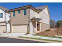 Two-story townhome boasting tan brick and light beige vinyl siding, and a 2-car garage at 4101 Fulson Dr, Lilburn, GA 30047