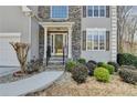 Welcoming front entrance with stone accents, professionally landscaped yard, and well-maintained walkway at 355 Holland Springs Way, Powder Springs, GA 30127