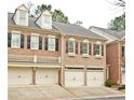 Two-story brick townhome featuring a symmetrical facade, dormer windows, and individual garages at 4703 Legacy Cove Ln, Smyrna, GA 30126