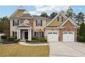Two story house with stone and shingle accents, two car garage, and landscaped yard at 2005 Creek Pointe Way, Villa Rica, GA 30180