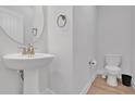 Small powder room with pedestal sink, toilet and gold fixtures at 11988 Lovejoy Crossing Pl, Hampton, GA 30228