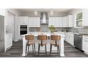 Modern kitchen with white cabinets, a center island, and gray backsplash at 317 Lavender Ln, Holly Springs, GA 30115