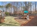 Large backyard with a wooden playset including a slide, climbing wall, and swings, perfect for outdoor fun at 10575 Stonefield Lndg, Johns Creek, GA 30097