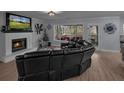 Cozy living room with a fireplace, large windows, and a comfortable black sectional sofa at 1175 Evergreen Oak Way, Dacula, GA 30019