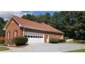 Side view of a brick home featuring a two car garage and well maintained landscaping at 2509 Fairweather Ct, Conyers, GA 30013