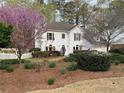Traditional home featuring manicured landscaping, flowering trees, and a white picket fence at 5440 Cameron Forest Pkwy, Johns Creek, GA 30022