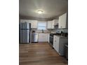 Modern kitchen with white cabinets, stainless steel appliances, and wood-look flooring at 2320 Cherokee Valley Dr, Lithonia, GA 30058