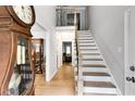 Bright foyer featuring hardwood floors, staircase, and an antique grandfather clock at 212 Teepee Trl, Whitesburg, GA 30185
