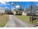 Street view of cozy home with painted brick, quaint porch, long driveway, and fenced yard at 2409 Swallow Se Cir, Atlanta, GA 30315