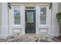 Elegant front door with decorative glass, flanked by sidelight windows and classic sconces at 1901 Shelburne Cv, Marietta, GA 30068