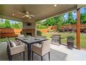 Outdoor dining area featuring a fireplace, ceiling fan, and stainless steel grill with backyard view at 231 Haney Rd, Woodstock, GA 30188