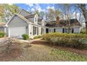 Gray home featuring attached garage, manicured landscaping, and brick chimney at 154 Great Oaks Ln, Roswell, GA 30075