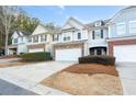 Three townhouses with attached garages and manicured landscaping in a suburban setting at 704 Woodland Pl, Woodstock, GA 30188