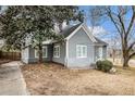 Charming home features gray siding, a stone foundation, mature trees, and a well-manicured lawn at 118 Strickland St, Fairburn, GA 30213