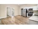 Bright kitchen features stainless steel appliances, white cabinets and granite countertops, with wood flooring and neutral paint at 118 Strickland St, Fairburn, GA 30213