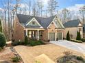 Traditional brick home with two-car garage, covered porch, and manicured lawn at 1545 Camden Cove Dr, Cumming, GA 30040